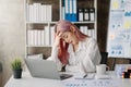 Asian woman who is tired and overthinking from working with tablet and laptop at modern office Royalty Free Stock Photo