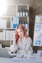 Asian woman who is tired and overthinking from working with tablet and laptop at modern office Royalty Free Stock Photo