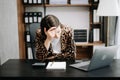 Woman who is tired and overthinking from working with tablet and laptop at modern office Royalty Free Stock Photo