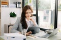 Woman who is tired and overthinking from working with tablet and laptop at modern office Royalty Free Stock Photo