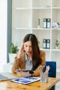 Woman who is tired and overthinking from working with tablet and laptop at modern office Royalty Free Stock Photo