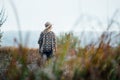 Woman in wide-brimmed felt hat and authentic poncho standing in high brown grass at foggy morning Royalty Free Stock Photo