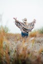 Woman in wide-brimmed felt hat and authentic poncho standing in high brown grass at foggy morning. Vertical orientation Royalty Free Stock Photo