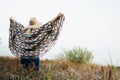 Woman in wide-brimmed felt hat and authentic poncho standing in high brown grass at foggy morning Royalty Free Stock Photo