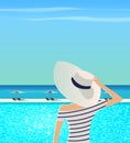 Woman in wide-brimmed hat is admiring sea.