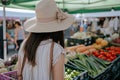 woman in a widebrimmed hat browsing through a farmers market Royalty Free Stock Photo