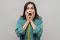 Woman with widely open mouth and big eyes looks at camera keeps palms on cheek stunned shocked face Royalty Free Stock Photo