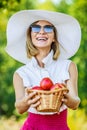 Woman wiht wicker basket holds red apples Royalty Free Stock Photo