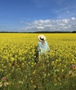 Woman on wild field blossom yellow flowers and bright sky with white clouds summer nature landscape, green field in countryside Royalty Free Stock Photo