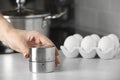 Woman winding up kitchen timer at white table indoors, closeup. Space for text Royalty Free Stock Photo