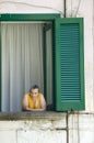 Woman in window in front of green shutters in Amalfi, Italy, Europe