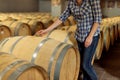 Woman winemaker checks oak wine barrels in which red wine is age