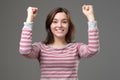 Woman winner raising arms, clenching fists, exclaiming with joy.