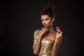 Woman winning - Young woman in a classy gold dress holding two red chips, a poker of aces card combination. Royalty Free Stock Photo