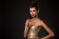 Woman winning - Young woman in a classy gold dress holding two red chips, a poker of aces card combination. Royalty Free Stock Photo