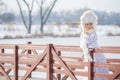 Woman Winter Fashion. Portrait of Sensual Caucasian Blond in Knitted White Dress and Kerchief with Fur Kokoshnik.Posing on Bridge Royalty Free Stock Photo