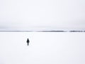 Woman in a winter jacket standing on the edge of a frozen lake. Royalty Free Stock Photo