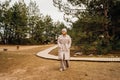 A woman in a winter jacket walks along a wooden path in a pine forest. Royalty Free Stock Photo