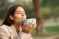 Woman in winter smelling coffee aroma in a park