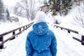 Woman in winter warm jacket and white hat walking in snowy winter mountains Royalty Free Stock Photo