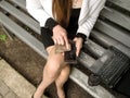 Woman wipes the screen of the mobile with a piece of cloth. Partial top view of the female body, a laptop and a glass of coffee