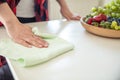 Woman wipes white table with wooden bowl