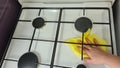 Woman cleaning a gas stove with yellow cloth