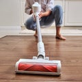 Woman with a wireless portable vacuum cleaner in the kitchen. Cleans Royalty Free Stock Photo