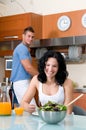 Woman wirh salad in the kitchen and man washing