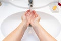 A woman wishing hands with water in bathroom sink. Desease prevention and hygiene concept. Useful, good habit