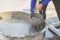 Woman woker scoop mixed cement into a bucket.