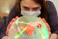 A woman is wondering about the future of the coronavirus on a ball of fate. Masked witch girl over crystal ball predicts the