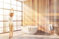 Woman in wooden bathroom corner with tub Royalty Free Stock Photo