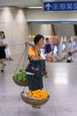 Woman with a wooden carrying pole selling fruits and water in Nanjing subway