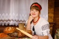 Woman with wooden rolling pin bakes bread