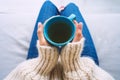 Woman in woolen cozy sweater warming cold hands with a mug of hot tea. Woman holding cup of tea.