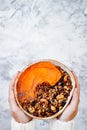 Woman in woolen sweater holding bowl with cinnamon granola, coconut yogurt, chia seeds and pumpkin puree. Healthy vegan smoothie Royalty Free Stock Photo