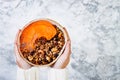 Woman in woolen sweater holding bowl with cinnamon granola, coconut yogurt, chia seeds and pumpkin puree. Healthy vegan smoothie Royalty Free Stock Photo