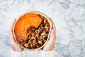 Woman in woolen sweater holding bowl with cinnamon granola, coconut yogurt, chia seeds and pumpkin puree. Healthy vegan smoothie Royalty Free Stock Photo