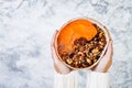 Woman in woolen sweater holding bowl with cinnamon granola, coconut yogurt, chia seeds and pumpkin puree. Healthy vegan smoothie