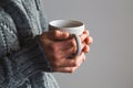 Woman in woolly gray sweater holding warm cup of tea