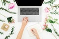 Woman work with laptop. Workspace with female hands, laptop, notebook and pink flowers on white background. Top view. Flat lay