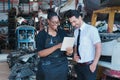 Woman work with man. Diversity of two people, black African worker woman using tablet with caucasian business manager in factory- Royalty Free Stock Photo