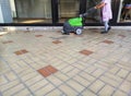 Woman at work washes floors with professional machinery
