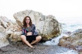 Woman workaholic working on a laptop while sitting on a rock on the beach Royalty Free Stock Photo