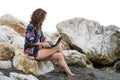 Woman workaholic working on a laptop while sitting on a stone on the beach Royalty Free Stock Photo