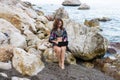 Woman workaholic works on netbook sitting on a stone on the beach
