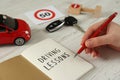 Woman with workbook for driving lessons at white wooden table, closeup. Passing license exam Royalty Free Stock Photo