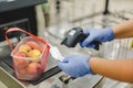 Woman or worker in blue medical gloves holding bar code scanner and scanning paper on peach fruit