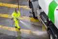 Woman worker cleaning a city road with high pressure water of a maintenance truck